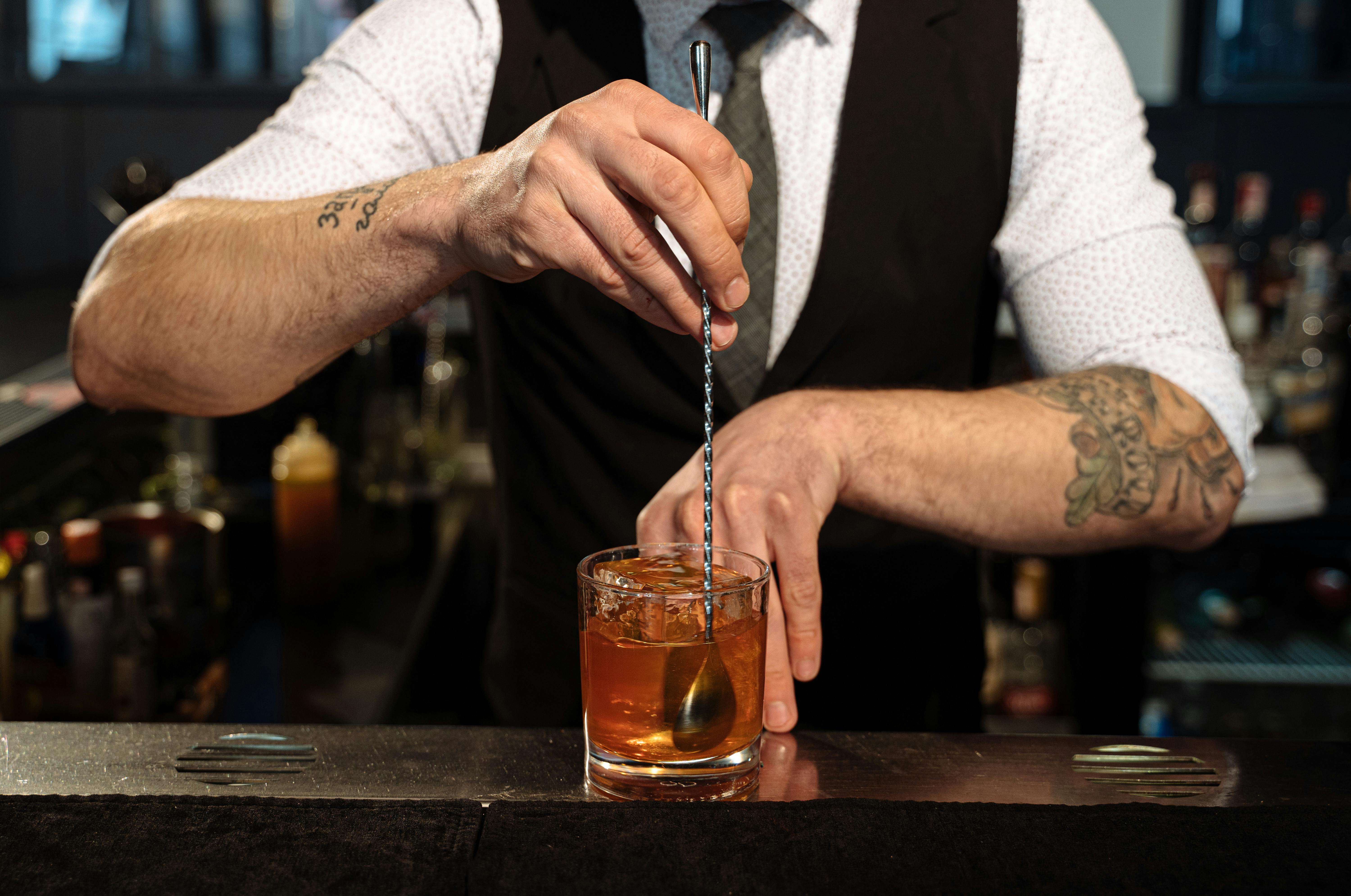 A bartender expertly blends a cocktail with ice, showcasing professional skills and style in Montreal